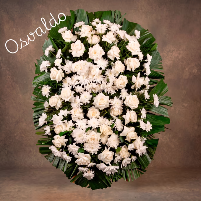Coroa oval de rosas brancas e crisântemos brancos por toda a superfície, com folhas de palmeira verde escuro abertas em leque na borda.